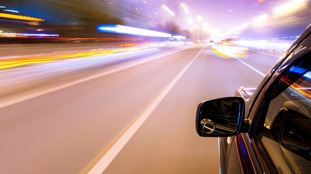 O iluminação borrada à medida que o carro dirige rapidamente na estrada
