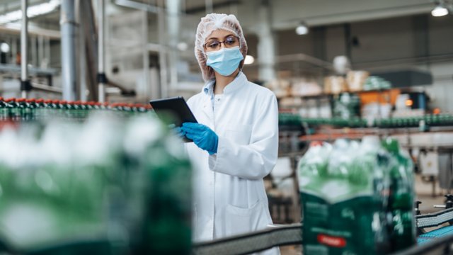 Ingeniera realizando una inspección de control de calidad en una planta de embotellado